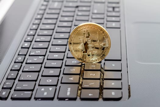 Studio shot of golden Bitcoin virtual currency on laptop. Close-up of front side.