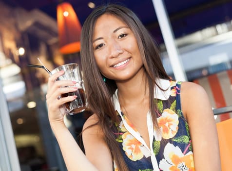 Close up portrait of a beautiful asian girl drinking a soda sitting on terrace