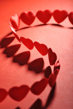 Chain of small red fabric hearts on a red background