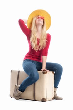 a blonde woman sits on a suitcase and waits