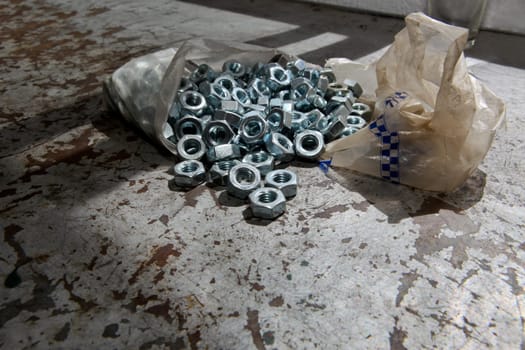 Plastic bag of load of new alloy nuts over a mechanic table