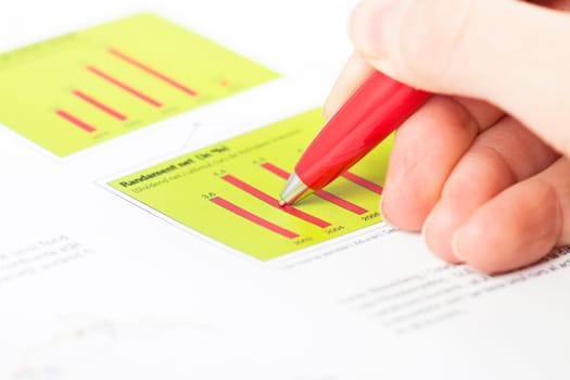 Close-up of female hand holding pen over business graph
