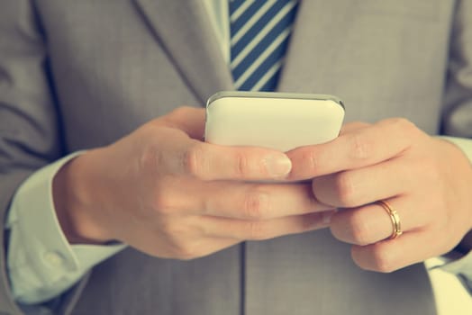 Close-up businessman hand using smart phone in retro tone.