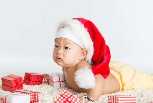 Asian santa hat baby boy with Christmas gift on floor.