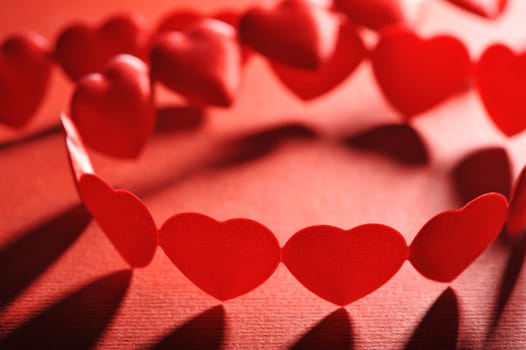 Chain of small red fabric hearts on a red background