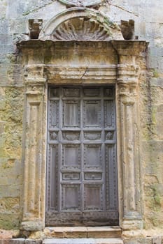 Ancient wooden church door surrounded by weathered plaster.