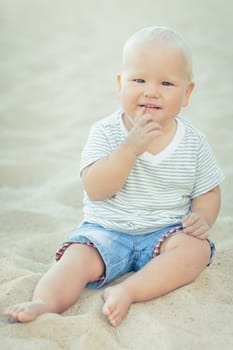 Cute baby sitting on a sand and smiling