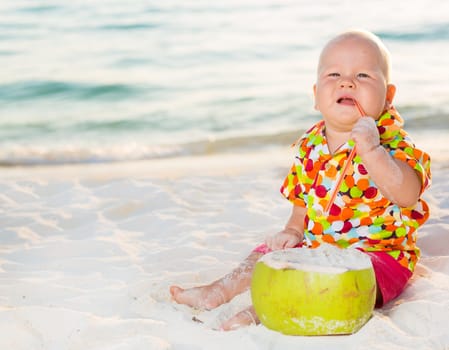 Funny baby with coconut on the beach
