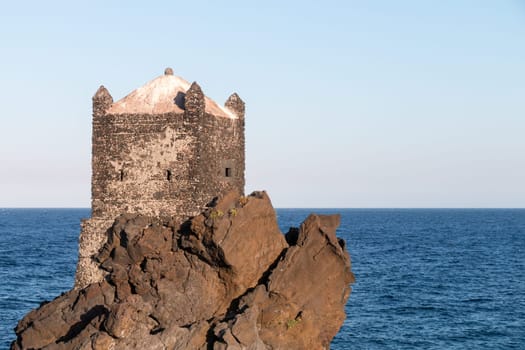 Medieval Tower build on lava stone in ionian sea Sicily