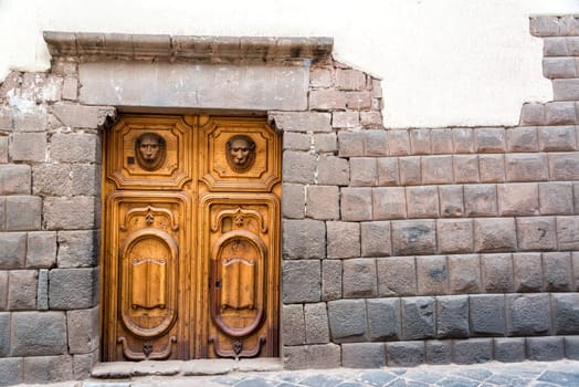 Inca stonework with a beautiful carved wooden door in Cusco, Peru