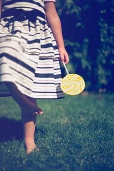Little girl holding a lollipop in her hand. Closeup.