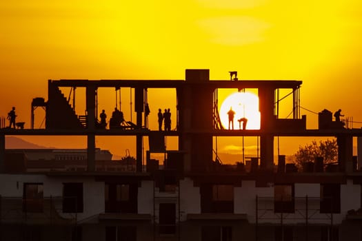 Silhouette of construction workers working on sunset