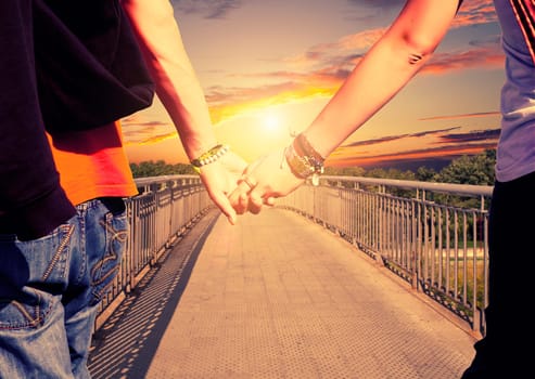 View of lovers couple holding hands on the bridge