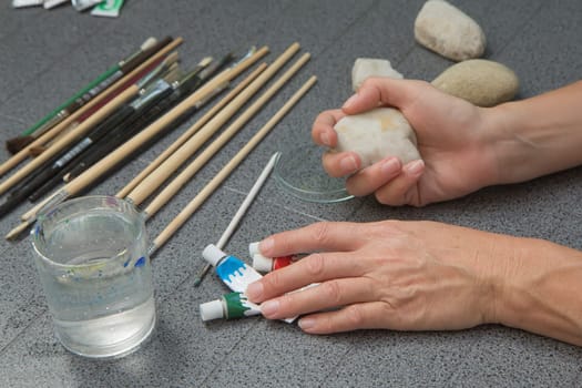 Handmade - stone painting. production decoration. Preparation for painting. Female hand are holding a blank stone.