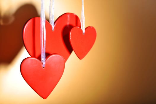 three red wooden hearts against a golden background