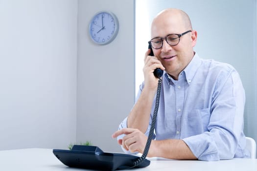 relaxed bald man talking on the phone with a little smile
