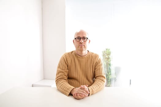 a bald nerdy man with sunglasses in an empty white office