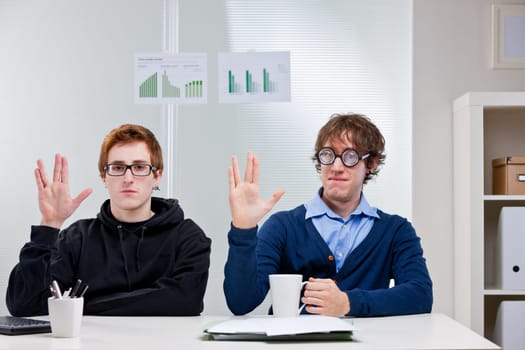 a couple of nerd office workers showing a very popular science fiction salutation
