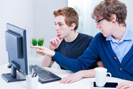a couple of young employees in an office working together to achieve common goals