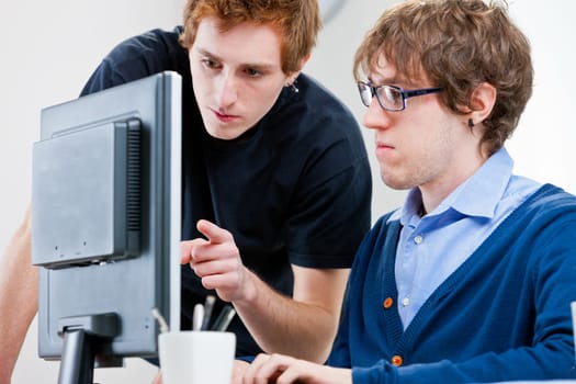 a couple of young employees in an office working together to achieve common goals