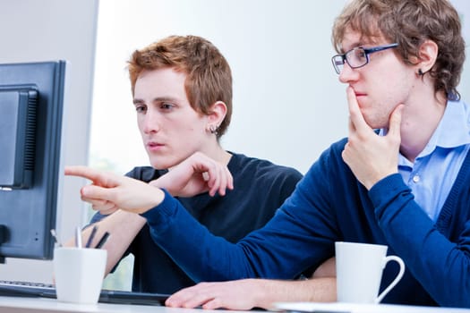 a couple of young employees in an office working together to achieve common goals