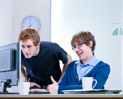 a couple of young employees in an office working together to achieve common goals
