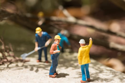 Miniature workmen clearing fallen trees on a sunny day