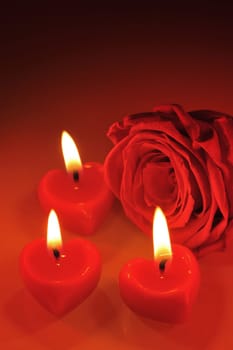 Three bright red candles in heart shape with red rose