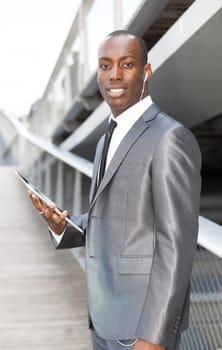 Portrait of a businessman with hands-free headset and using electronic tablet