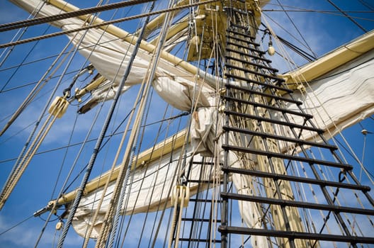Sails and tackles of a sailing vessel on a background of the sky
