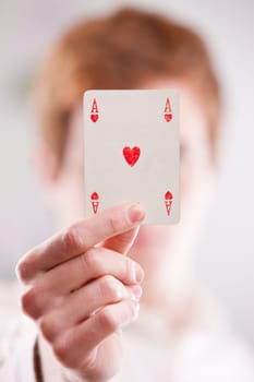 a red headed guy showing off an ace card of hearts