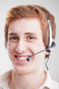 A smiling young man with red hair smiling and wearing an headset
