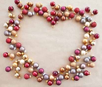 Heart made of colorful Christmas tree balls on wrapping paper