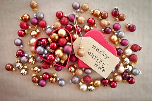 Red heart box with colorful Christmas tree balls on wrapping paper