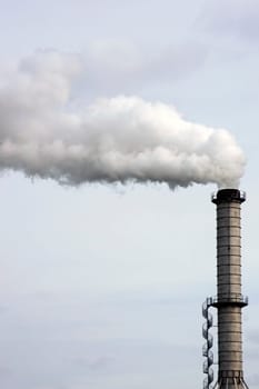 The photograph of a smouldering chimney with a spiral staircase of an industrial plant.