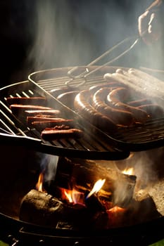 The photograph of a charcoal grill with sausages.