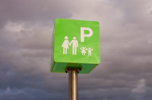 Reserved car park pole green sign for family against cloudy sky sky