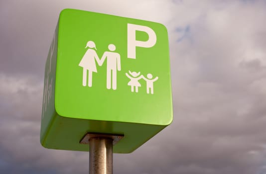 Reserved car park pole green sign for family against cloudy sky sky