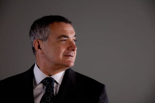 Senior with suit and tie very self confident looking at his side
