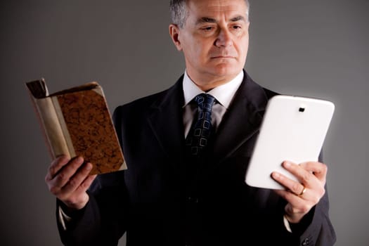 An old expert comparing a book and a tablet maybe an e-book to check which one is the best