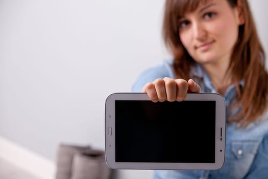 young smiling girl showing off a tablet with a blank screen in which you can put your text or pictures
