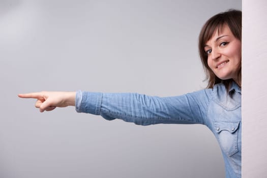 girl pointing out with her entire arm behind the wall