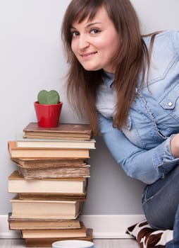 lovely girl loving her plant and her books sitting on the floor of her house in relax