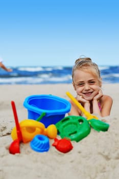 Little girl playing on the sand beach.