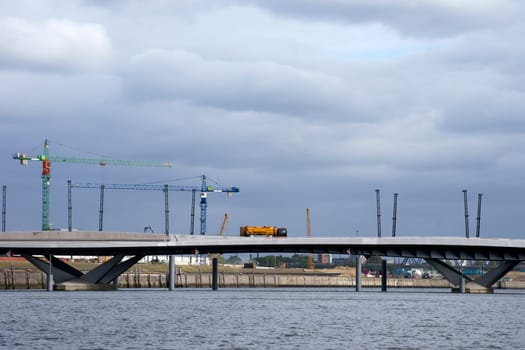 A lorry crosses a newly built bridge with construction sites and cranes.