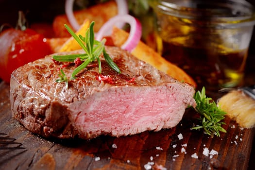 Succulent tender rare beef steak grilled to perfection sliced through to show the texture seasoned with fresh rosemary and salt