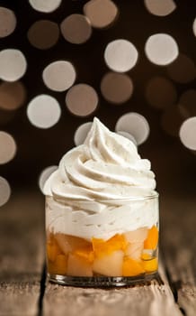 Macro Tasty Frozen Yogurt Above Mango Slices on Round Glass Container. Placed on Wooden Table.