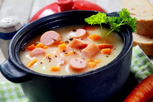 Close up Mouth Watering Hot Creamy Soup Dish with Sausage on Cloth at Wooden Table.