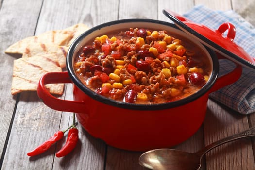 Close up Appetizing Spicy Meaty Recipe on Red Pot Placed on Wooden Table Ready to Eat.