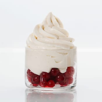 Fresh healthy redcurrants topped with frozen vanilla yogurt in a clear glass bowl for a delicious dessert